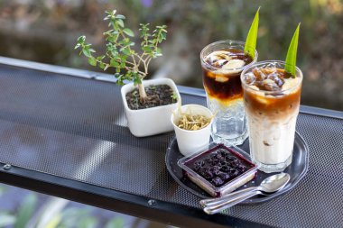 Sütle karıştırılmış buzlu kahve. Hindistan cevizi suyu ve hindistan cevizi etiyle karıştırılmış kahve. Üstüne de yaban mersinli cheesecake ile servis edilen aroma için pandan yaprakları. ve kurutulmuş taro.