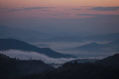 Güneş doğmadan önce dağların tepesindeki bir sabah manzarasının arkaplan resmi ve sisli bir deniz..