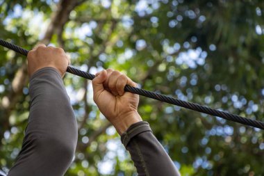 Halatla kaymak için bir ip. Ve halatı tutan el doğal arka planda.