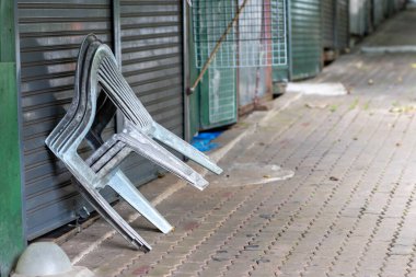 Kapalı dükkanların önündeki kaldırımda seçici odaklı plastik sandalyeler