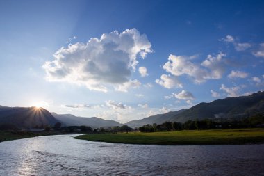 Manzara, nehir, dağlar, yeşil çimenler, gün batımı, parlak gökyüzü.
