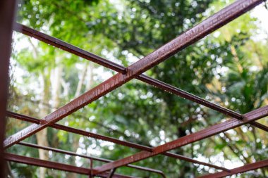 Kırmızı paslanmaz boya ile boyanmış seçici odaklı çelik yapı. yağmurla ıslanmış çelik yapı yeşil doğal arkaplan