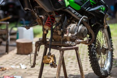 Arka tekerleği çıkarılmış bir motosiklet atölyesinde seçici odaklı motosiklet motoru.