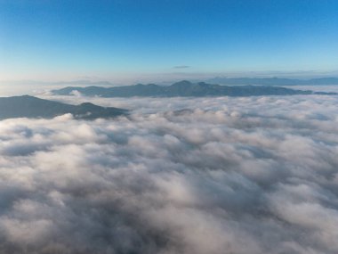 Yüksek açılı bir manzara, yoğun sis, sisle kaplı doğal orman dağları. Parlak bir gökyüzü ve güzel bir manzara bir dron ile gökyüzünden görülebilir..