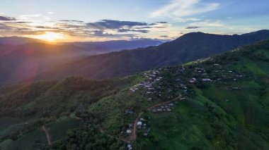 Yüksek açılı bir manzara, dağların ortasındaki köy, doğal orman, akşam günbatımı, açık gökyüzü, ormanın ortasındaki köy. İnsansız hava aracıyla yakalanan güzel manzara..