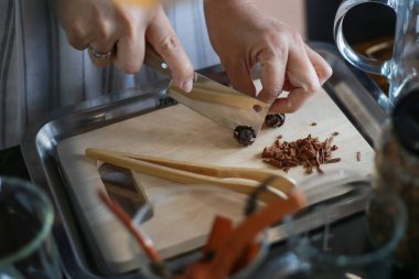 Kurutulmuş baharatlar bir baharat dükkanındaki ahşap bir kesme tahtasının üzerinde, bitkilerin kokusu ve tazeliği için doğranıyor..