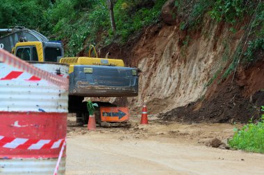 Toprak yollarda seçici bir odak kazıcı. Kırsal yol onarım bölgelerinde heyelan var. Kepçeli yol onarımı. Yağmur mevsiminde, yol heyelan tarafından hasar gördü.