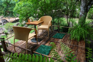  Tayland 'da ormandaki bir kafede yemyeşil ağaçların arasında masa ve sandalyeler..