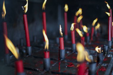 Sayısız kırmızı mum loş ışıkta, kutsal mekânda sıcak ve ruhani bir ışık saçarak yanar. Yanıp sönen alevler huzur ve tefekkür duygusunu çağrıştırıyor, bir saygı atmosferi yaratıyor.