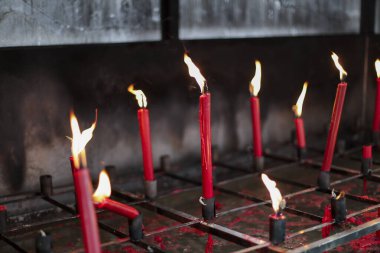 Kırmızı mumlar parlak ve kutsal tapınak ortamını yakar, sıcak bir parıltı yayar. Yanıp sönen alevler, duayı ve saygıyı simgeler. Kutsal içinde huzur dolu bir ruhani atmosfer yaratır.