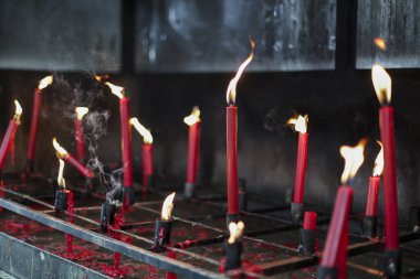 Kırmızı mumlar yavaşça sönük, kutsal ayar derin huzur ve ruhani saygıyı çağrıştırıyor. Sıcak, titrek parıltıları sessiz mekanı aydınlatır. Umudu, bağlılığı ve ciddiyeti sembolize eder.