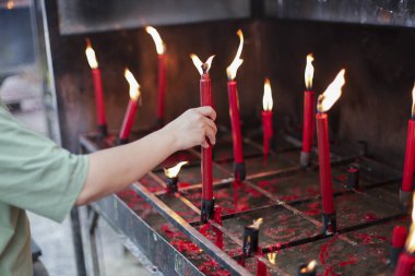 İnsan eli dikkatli bir şekilde kırmızı mum yakar ve kutsal tapınakta yanıp sönen diğer alevlere katılır. İbadet ruhsal huzuru ve umut dolu duayı iletir. Huzurlu bir atmosfer yaratır.