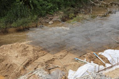 Nehir kıyısı toprak dengelenmesi için kum üzerindeki tel örgüyle zemin hazırlığı