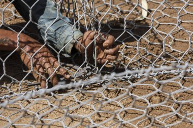Çalışan eller, metal tel örgüleri birbirine bağlar. Bu da inşaat için gereken özeni gösterir. Açık havada yapılan çalışmalar gabion ağını güvenli hale getirmeyi, kuru zemin oluşturmayı, odaklanmış el işçiliğini göstermeyi içerir.