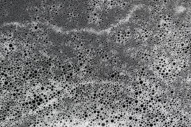 Sayısız koyu baloncuklar ilgi çekici bir soyut doku sıvı yüzeyi oluşturur. Benzersiz gri tonlama deseni, tasarım projeleri için detaylı ve organik yakın çekim görüntüsü sunarak dinamik görsel efekt yaratır