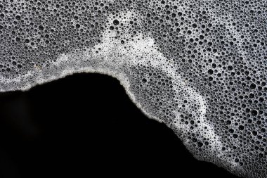 Narin beyaz köpük kabarcıkları koyu siyah arkaplan üzerinde büyüleyici bir doku oluşturarak ilginç ve soyut bir model oluşturur. Temiz köpüklü köpükler saflığı, tazeliği ve sükuneti çağrıştırıyor.