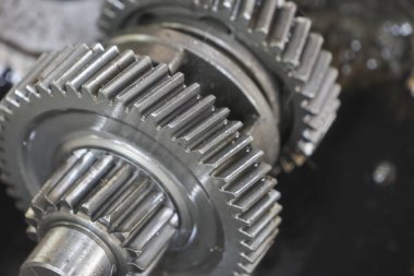 Karmaşık dişleri ve güçlü bağlantıları olan, mühendislik hassasiyetini ve mekanik işlevini sembolize eden iki metalik dişliyi kapatın.