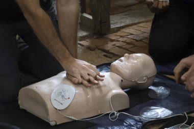 Kalp masajı mankeni insanlar tarafından acil durum canlandırma pratiği için kullanılıyor, elleri göğsüne baskı uygulayan, umut ve hazırlık yapan hayat kurtarma tekniklerini gösteriyor.