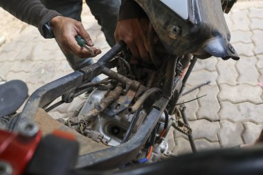 Mekanik ustalıkla çalışan motosiklet motoru uzmanlık ve hassasiyeti el çabukluğu ile gösteriyor. Tamirci dikkatle dikkatli bir şekilde aracın bakımına ve mekanik görev tutkusuna odaklanıyor.