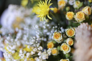 Yumuşak sarı güller, küçük beyaz çiçekler ve canlı sarı kasımpatılar ile dolup taşan narin neşe ve doğal güzelliği çağrıştıran narin çiçek düzenlemeleri.