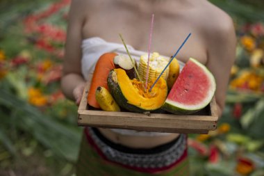 Huzurlu kadın ruhani tören için meyve tepsisi sunuyor. Geleneksel ritüel, bağlılık ve kültürü tütsü, balkabağı, muz ve karpuzla göstermektedir.
