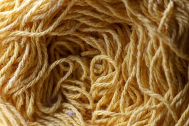 Karışık sarı yün ipliğin makro görüntüsünü kapat. Yumuşak, altın elyafın karmaşık dokusu işçilik için sıcak, karmaşık ve güzel bir arkaplan yaratır.