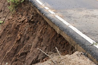 Toprak erozyonuna ve yol hasarına yol açan tehlikeli toprak kayması. Asfalt karayolu doğal afetten çöktü. Ülke yolunda yıkım ve yıkım tehlikesi var.