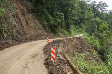 Kırsal alandaki toprak toprak toprak toprak toprak toprak toprak toprak toprak kayması sonucu hasar gördü. Uyarı işareti sürücüleri tehlikeli toprak kayması ve dağ geçidinde toprak erozyonu konusunda uyarıyor
