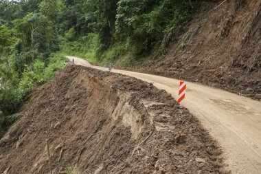 Tehlikeli heyelan yol hasarına ve kırsal dağ yolunda çamurla toprak erozyonuna neden oluyor. Orman yolu çökme tehlikesi uyarısı gösteriyor.