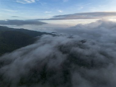 Huzurlu beyaz bulutlarla kaplı görkemli dağlar nefes kesici hava manzarası yaratır. Berrak mavi gökyüzü altındaki sakin sabah manzarası derin bir sükunet ve doğa harikası hissi uyandırıyor.