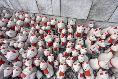 Beyaz seramik tilki heykelleri geleneksel Japon tapınağında büyüleyici ruhani atmosfer yaratır. Kalabalıkları derin kültürel saygıyı ve kutsal geleneği yansıtıyor.