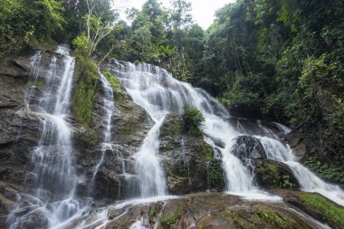 Görkemli katmanlı şelale canlı yeşil tropikal ormanlardan aşağı iner. Güçlü akan sular zarif bir şekilde antik kayaların üzerine dökülür. Huzur veren doğal bir manzara yaratır.