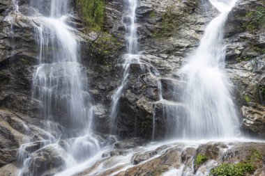 Engebeli kayaların üzerinden çağlayan şelale güçlü, dingin ve ferahlatıcı doğal güzellikleri çağrıştırıyor. Beyaz su zarifçe alçalıyor, sakin bir ortam ve huzurlu bir ses yaratıyor.