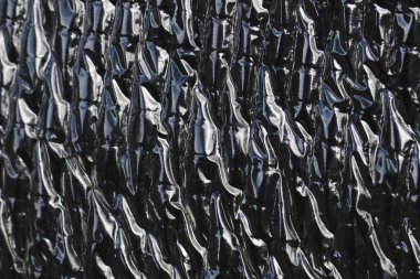 Abstract view of wrinkled and reflective heat protection sheet. This metallic insulation foil creates an industrial texture and dark, shiny background for modern design