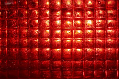 Intense red light background with glowing geometric grid pattern. This abstract, vibrant texture from warning lamp or reflector creates luminous, square design