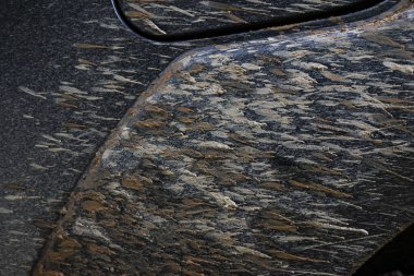 Splattered mud, dirt, and grime create rough, rugged texture vehicle fender. Brown, black, and grey elements form an abstract pattern, evoking sense of outdoor adventure and challenge of offroad