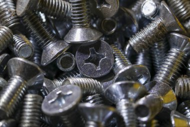 Detailed macro view of large pile of metal screws. industrial background shows an abundance of shiny steel hardware for construction, fastening and repair projects