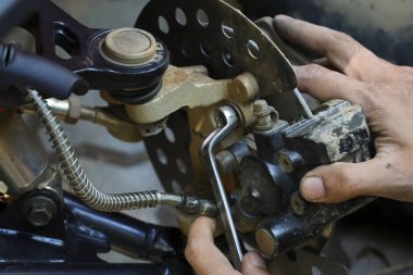 Odaklanmış tamirci fren onarımı ve araç bakım hizmeti veriyor. El, atölyede tamirat yapmak için araç kullanır. Bu profesyonel çalışmada ayrıntılı el emeği gösteriliyor