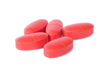 Kırmızı oral ilaç hapları beyaz arkaplanı kapatır.