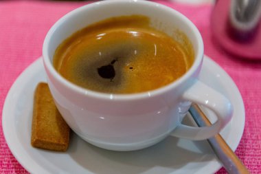 Siyah kaşıkla beyaz bir fincanda espresso içerken yakın plan bir fotoğraf..