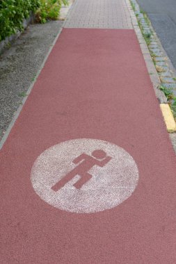 Üzerinde beyaz bir işaret olan kırmızı bir kaldırım.