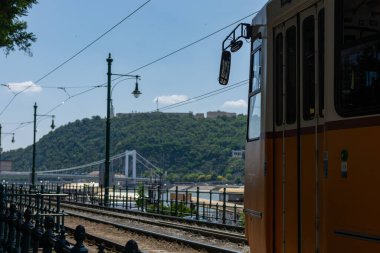 Tren raylarından bir köprünün yanına gidiyor.