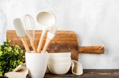 Background with kitchen utensils standing on wooden countertop.