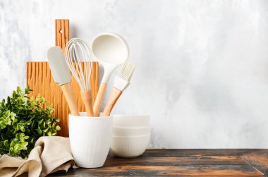 Background with kitchen utensils standing on wooden countertop.
