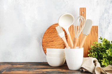 Background with kitchen utensils standing on wooden countertop.