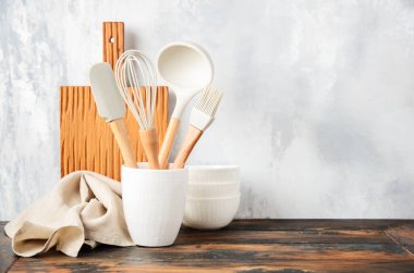 Background with kitchen utensils standing on wooden countertop.