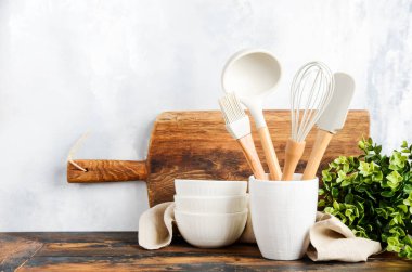 Background with kitchen utensils standing on wooden countertop.
