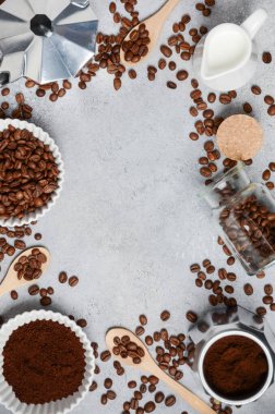 Kahve çekirdekleri ve öğütülmüş kahve, dokulu bir yüzeyde demleme aletleriyle güzelce düzenlenir. Sıcak ve davetkar bir kahve deneyimi uyandırır.