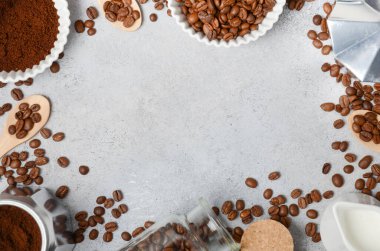 Kahve çekirdekleri ve öğütülmüş kahve, dokulu bir yüzeyde demleme aletleriyle güzelce düzenlenir. Sıcak ve davetkar bir kahve deneyimi uyandırır.