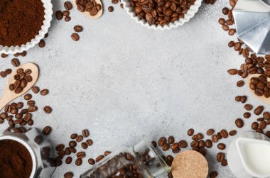 Kahve çekirdekleri ve öğütülmüş kahve, dokulu bir yüzeyde demleme aletleriyle güzelce düzenlenir. Sıcak ve davetkar bir kahve deneyimi uyandırır.